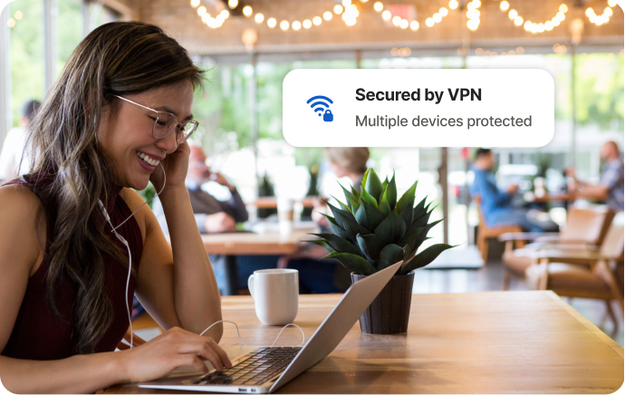 Kvinne på kafé som ler av noe på en bærbar PC