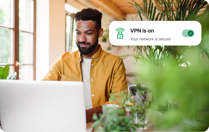 Mann omgitt av planter som smiler mot en bærbar PC